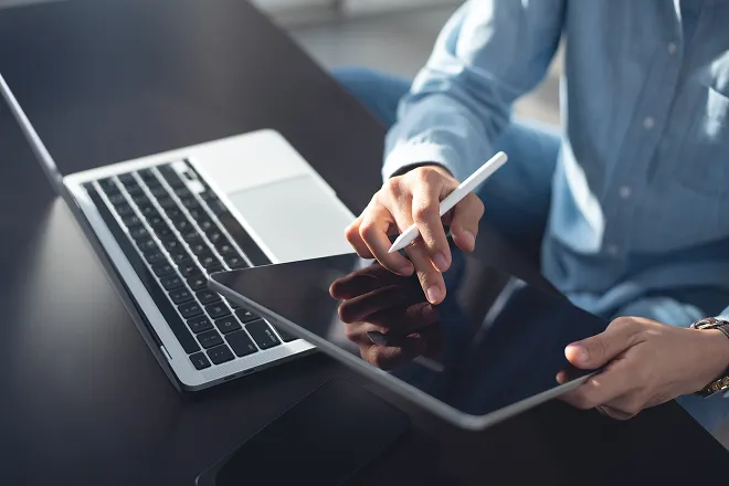 Man reviewing health insurance policies on his laptop and tablet