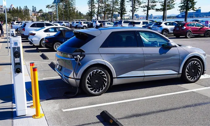 A grey Hyundai Ioniq 5 using a charging station in a waterfront parking lot in Newcastle, New South Wales, Australia.