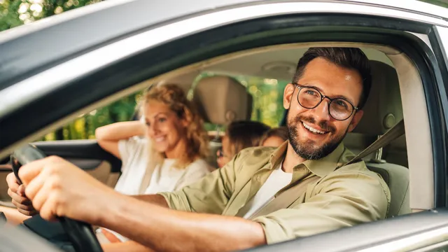 Portrait of a smiling man driving a car with his wife and child