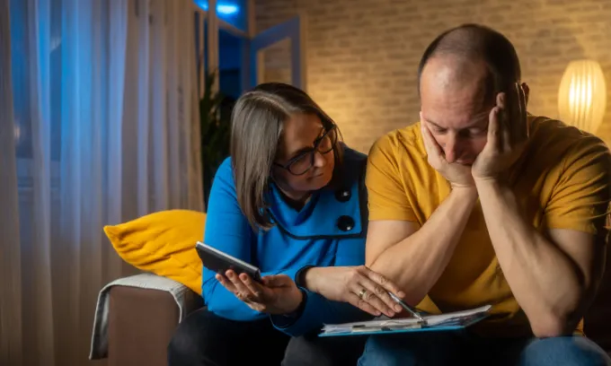 Couple looking appearing upset when looking at bills.
