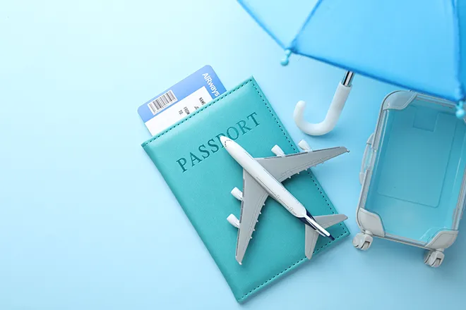Graphic representing travel insurance, showing model plane, passport, suitcase and umbrella