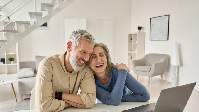Two elderly people look at a screen smiling