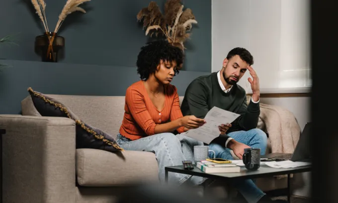 Couple sitting on the couch looking at bills.