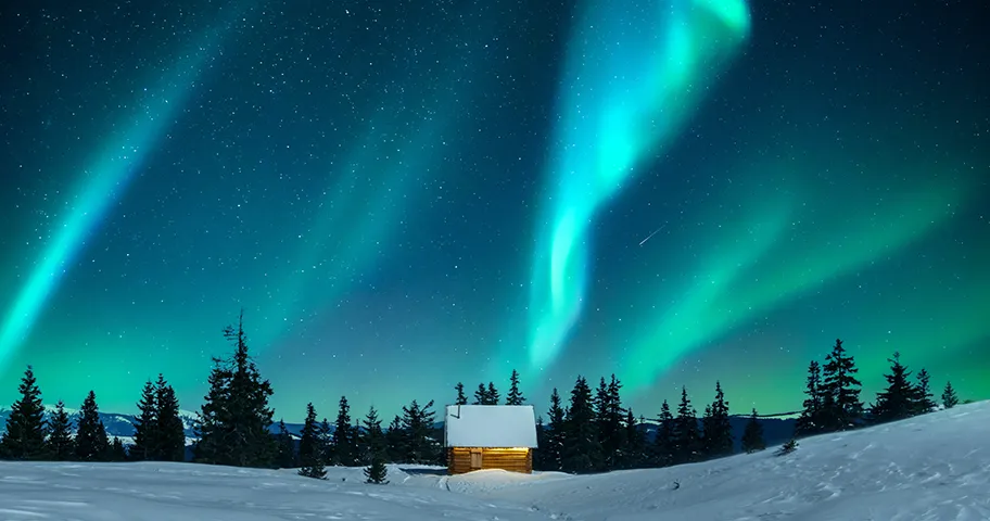 Northern lights above a cabin in a snowy forest