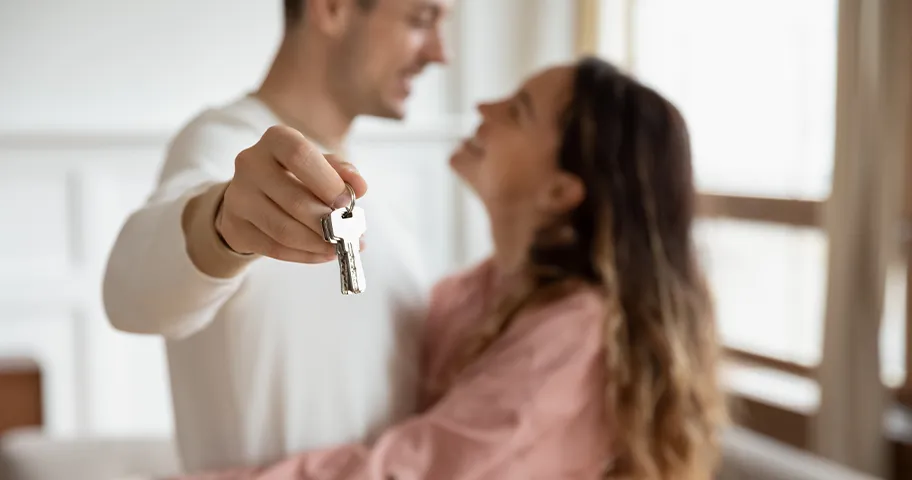 Young first home buyer couple embracing holding keys