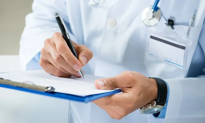 A doctor writes notes using a clipboard