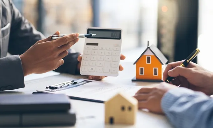A mortgage broker shows a potential rentvestor some figures on a calculator.