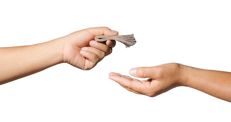 Close-up of two hands, one passing a wad of notes to the other