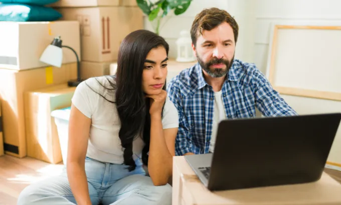 Couple looking for rental properties with boxes behind them. 