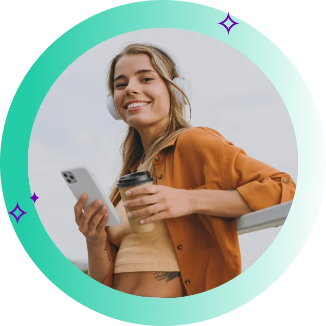 A young woman holds her mobile phone in one hand and a cup of coffee in the other.