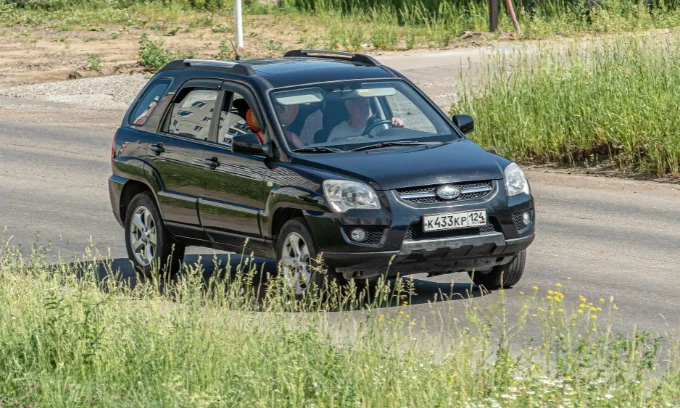 Kia Sportage being driven by an elderly person through unkempt land