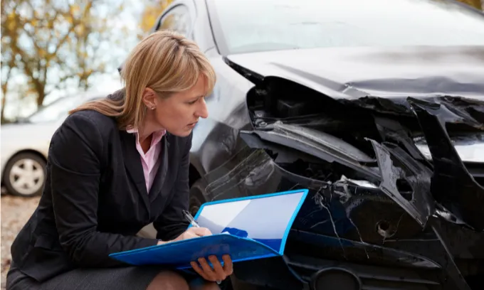 A loss adjuster lady looks at a smashed up car