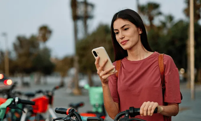 Woman looking at phone outdoors, checking mobile signal